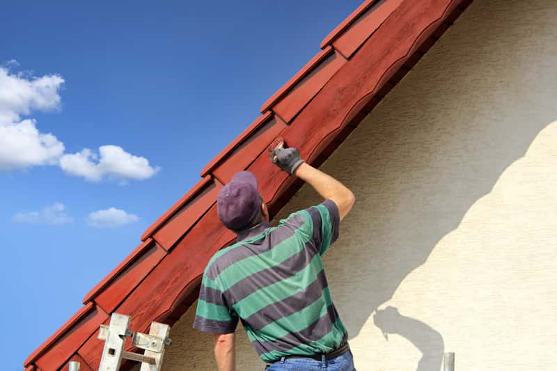 Mężczyzna podczas malowania dachu